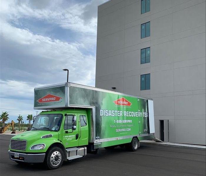 large SERVPRO box truck in front of commercial building with back ramp down to unload equipment