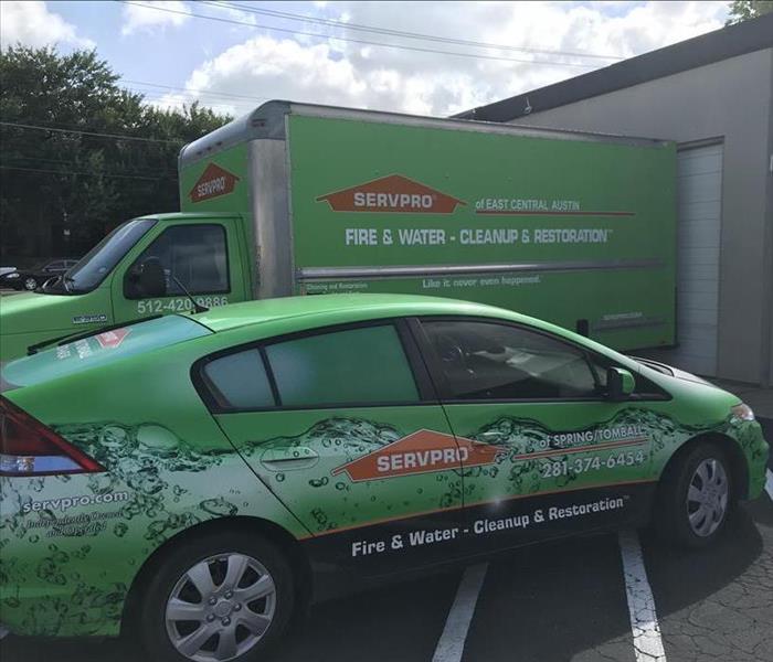 green car with SERVPRO information on side, green box truck behind car with SERVPRO information on side of truck