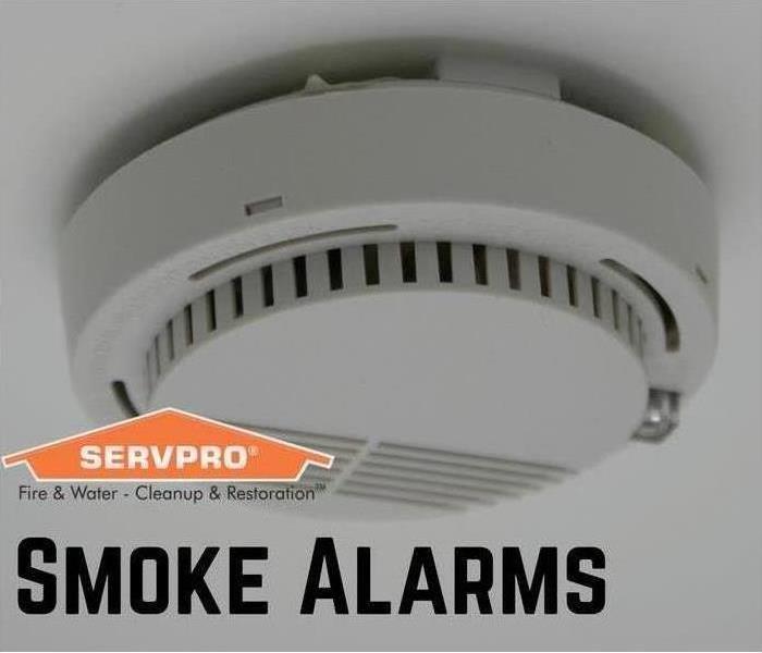 smoke detector on ceiling with orange servpro house in bottom left corner and "smoke alarm" under the servpro house. 