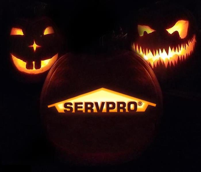 black background with jackolanters lit up. two with carved faces, one with SERVPRO house logo carved