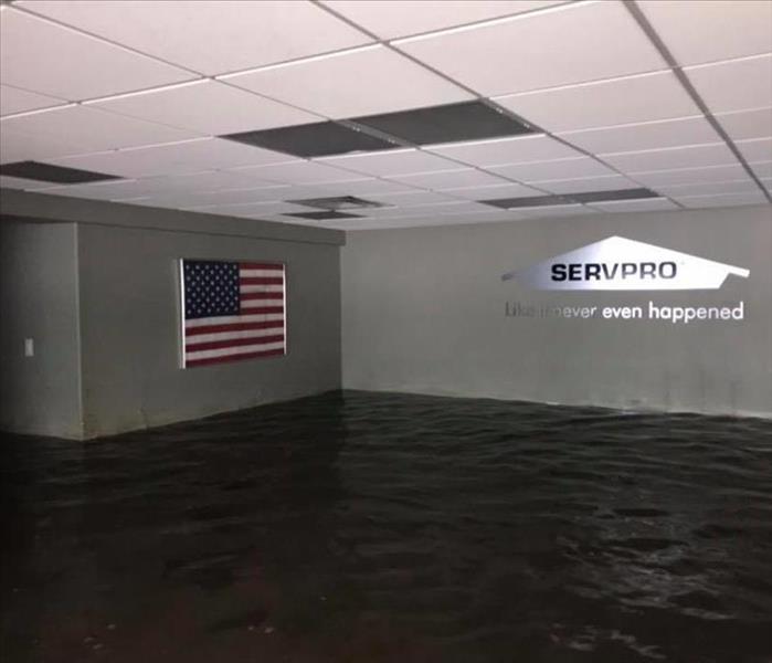 commercial building with water halfway up the walls. american flag on left wall, servpro house logo on right wall