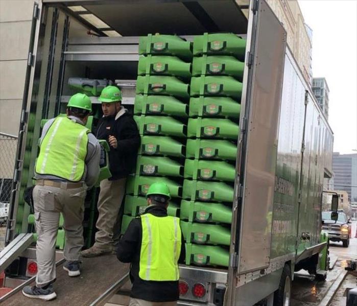 large SERVPRO truck, employees unloading green drying equipment.